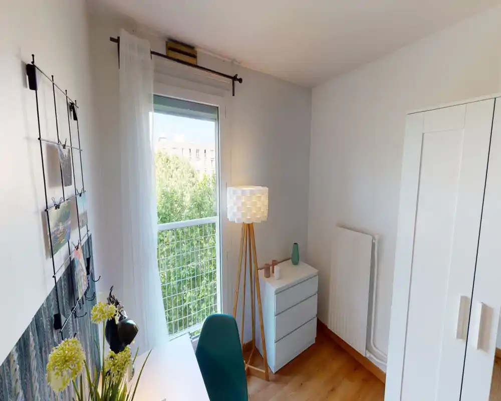 Coin chambre/bureau lumineux et moderne avec une grande fenêtre et un mobilier minimaliste — lampadaire, commode et armoire forment un espace paisible et bien éclairé, idéal pour se reposer ou travailler.