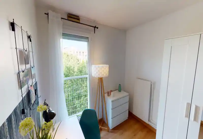 Coin chambre/bureau lumineux et moderne avec une grande fenêtre et un mobilier minimaliste — lampadaire, commode et armoire forment un espace paisible et bien éclairé, idéal pour se reposer ou travailler.