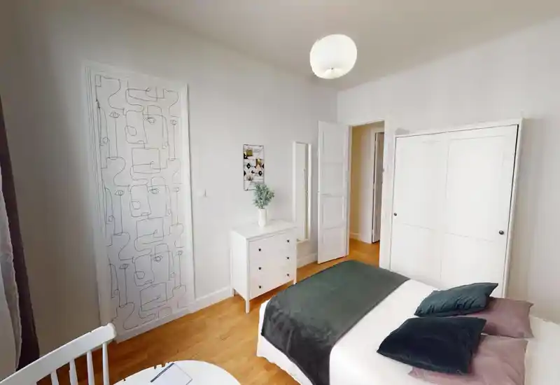 Distorted photo of a bedroom with a visible bed and light-colored walls; image shows heavy digital artifacts but suggests a simple, bright sleeping area.