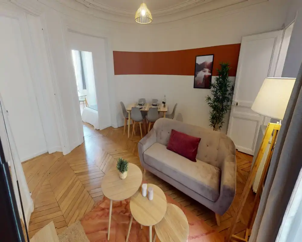 Salon lumineux et élégant avec canapé compact, tables basses, coin repas et parquet — un espace chaleureux pour se détendre et dîner.