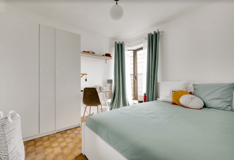 Bright, neatly styled bedroom with a large bed, coordinating curtains and a small desk by the window — ideal for restful stays and remote work.