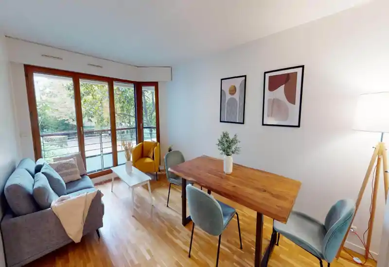 Salon lumineux et bien mis en scène avec canapé confortable, fauteuil d'appoint, table basse et table à manger en bois près de grandes fenêtres donnant sur la verdure — parfait pour se détendre et recevoir.