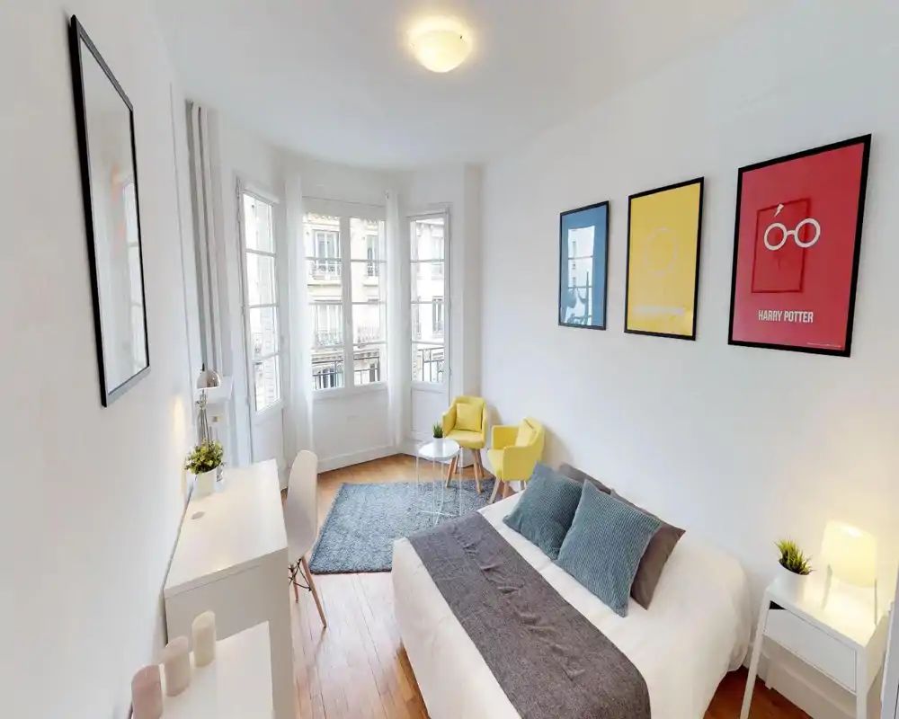 Salon lumineux et moderne avec canapé, tapis et affiches colorées au mur, offrant un espace détente confortable au style contemporain.