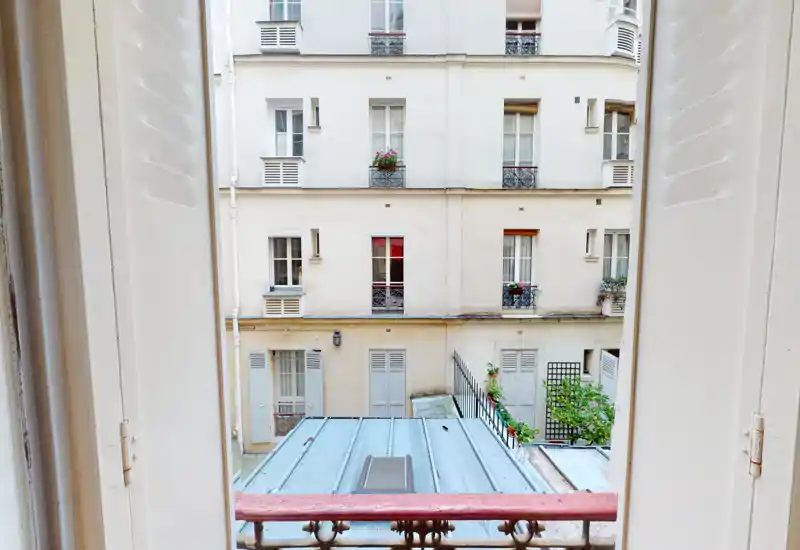 Piccolo balcone/visuale dalla finestra su un cortile con facciate d’epoca e fioriere: ottimo per mostrare luce naturale e carattere del quartiere.