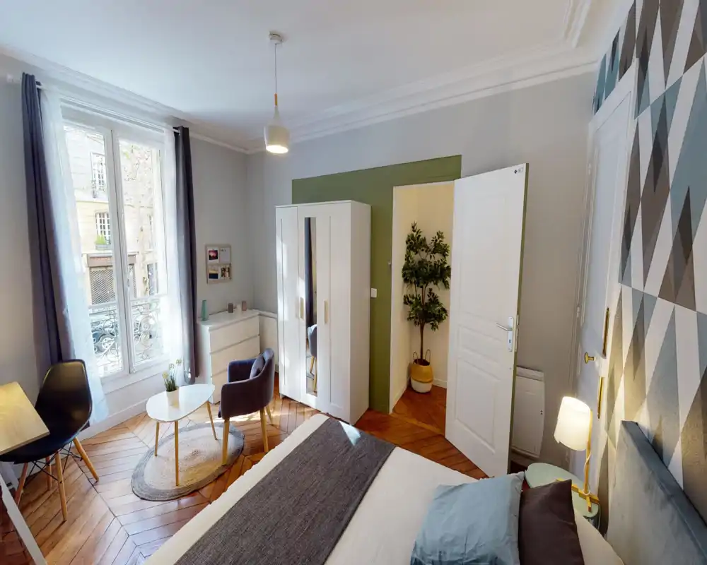 Camera da letto luminosa e moderna con ampia finestra, comodo letto, armadio e zona relax, perfetta per un affitto in città.