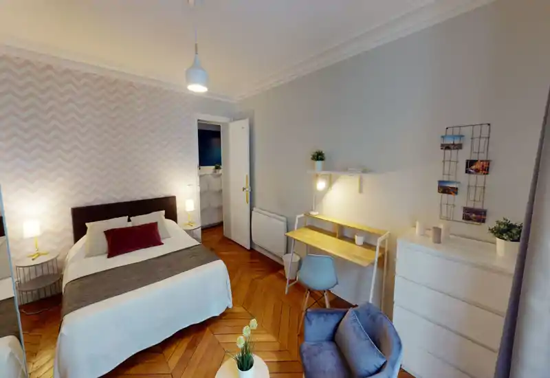 Spacious, well-decorated bedroom with a double bed, bedside lamps, patterned accent wall and a small workspace — bright and inviting for guests.