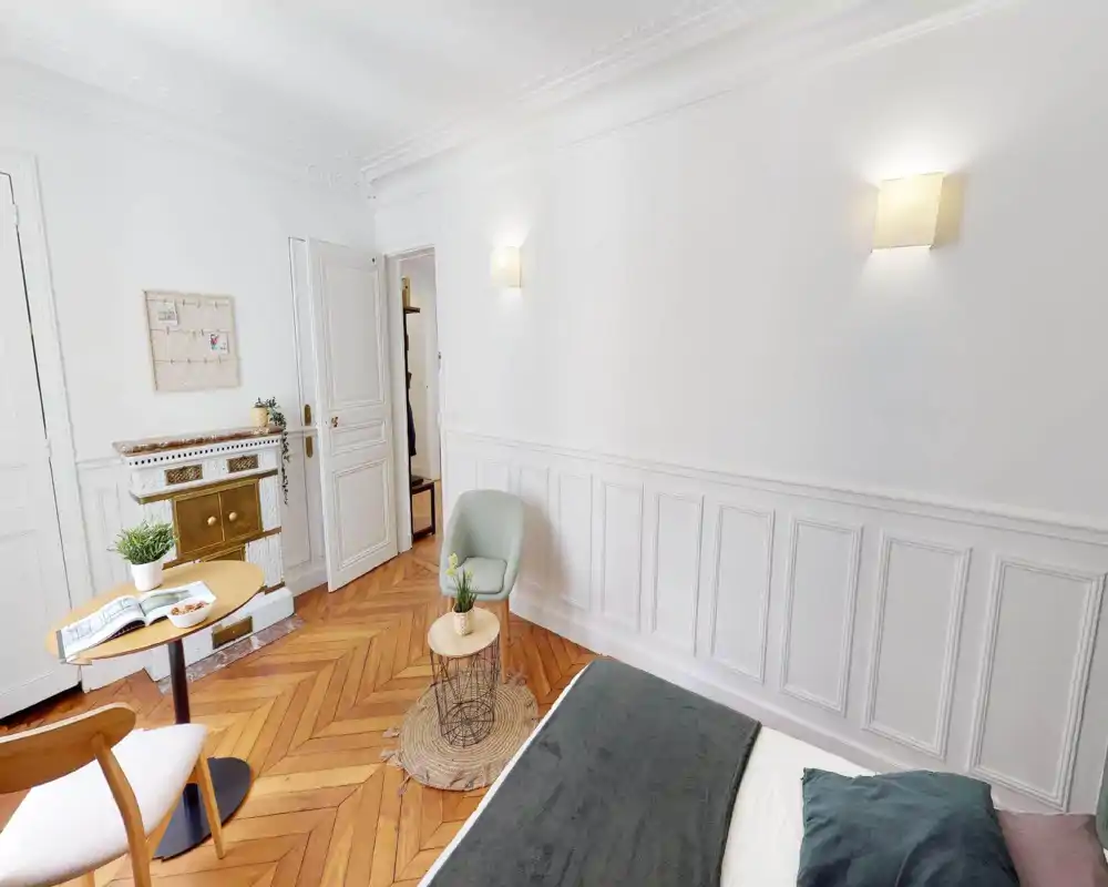 Spacious living area with seating and soft textiles; bright, airy feel despite image artifacts.