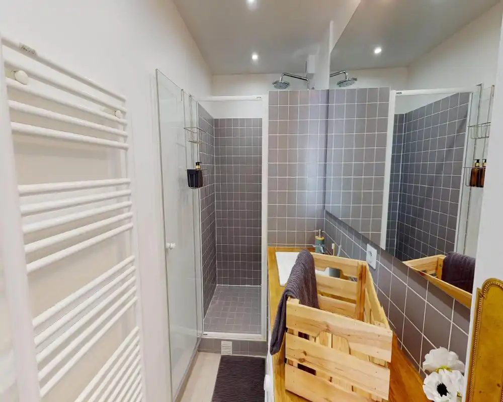 Modern tiled bathroom with a walk-in shower, wooden vanity top and large mirror; bright, neatly styled space ideal for rental listings.