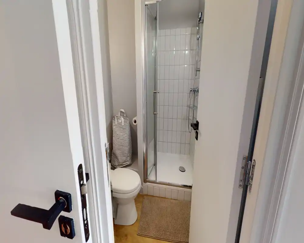 Compact, well-lit bathroom with a tiled shower cubicle, toilet and neutral decor — practical and tidy.