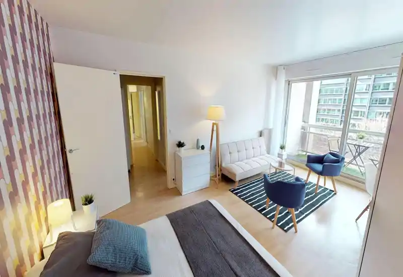 Bright, modern bedroom with a comfortable double bed, cozy textiles and a sitting area opening onto a balcony with large windows that flood the room with light.