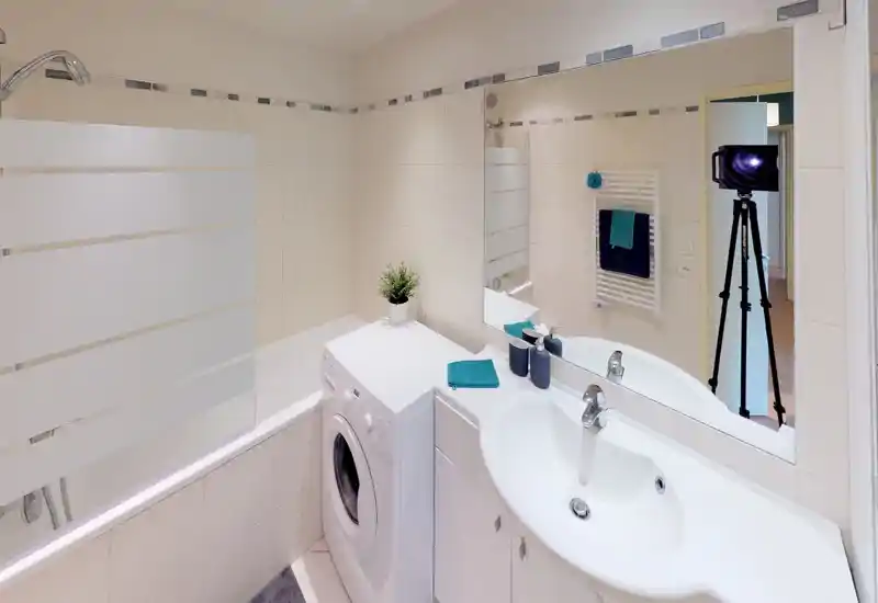 Bright, modern bathroom with a bathtub/shower, sink with countertop and mirror, and a washing machine; neutral tiles and teal accents create a fresh look.