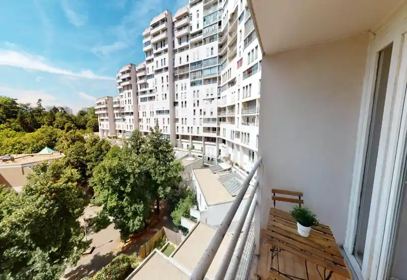 Balcony/terrace view showing trees and neighboring buildings through large curved openings; image has strong digital artifacts but conveys an outdoor perspective.