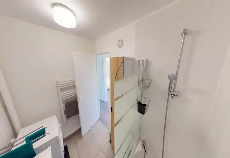 Small modern bathroom with a tiled shower area, glass partition and wall-mounted showerhead. Bright, clean and simply furnished — ideal for short-term rentals.