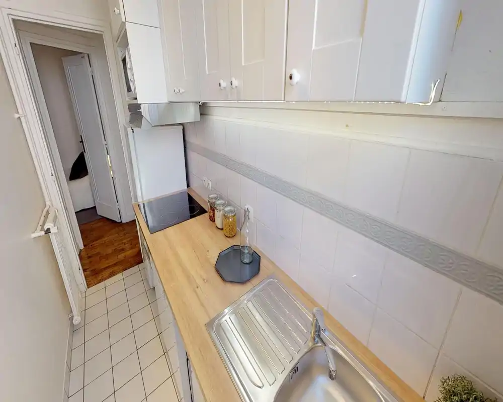 Cucina stretta e luminosa con piano in legno, piastrelle e lavabo integrato; piano cottura compatto e mobili contenitori per un uso efficiente dello spazio.