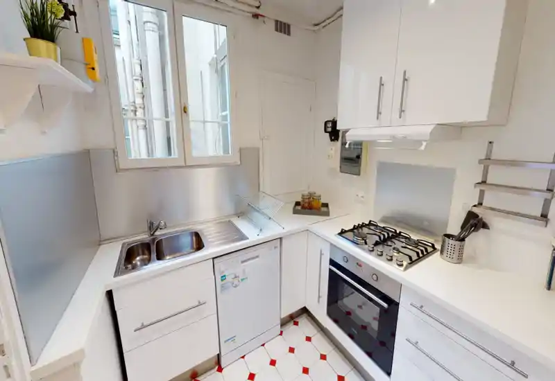 Bright, compact modern kitchen with white cabinets, stainless steel sink, gas hob and built-in oven — tidy layout ideal for short-term rentals.