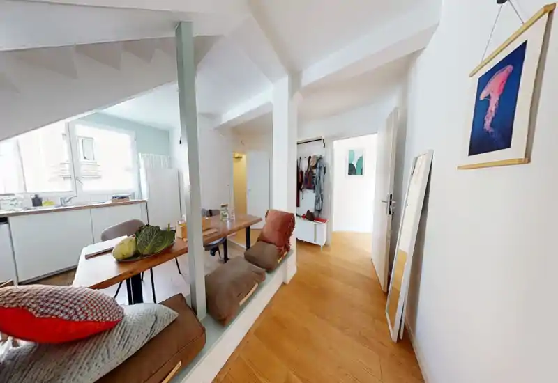 Espace de vie lumineux et chaleureux avec banquette intégrée, table en bois et grande fenêtre offrant une belle lumière naturelle — un endroit accueillant pour se détendre et dîner.