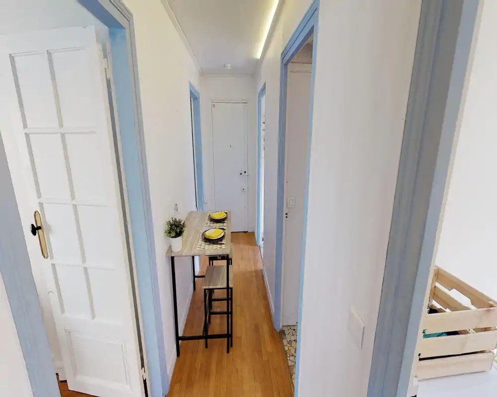 Narrow entrance/hallway with light wood flooring, pale walls and a slim console table set with two place settings — ideal for a compact dining setup in a corridor.