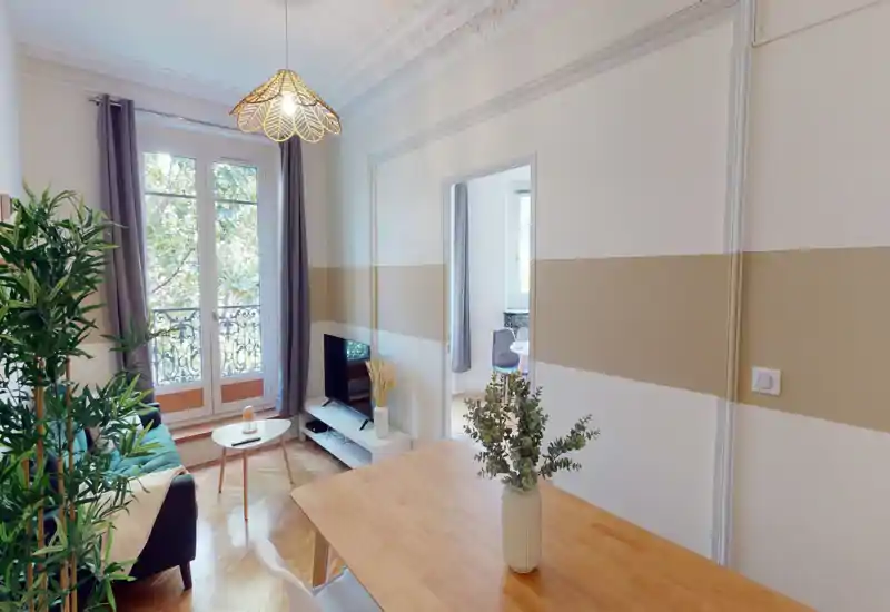 Soggiorno luminoso e stiloso con ampie finestre alla francese, divano confortevole, mobile TV e tavolo da pranzo in legno in primo piano; piante e tessuti creano un'atmosfera accogliente.