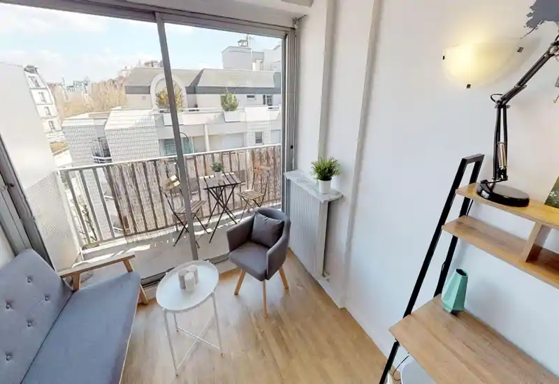Balcon/terrasse extérieure avec rambarde et skyline urbain visibles ; l'image est très dégradée mais laisse deviner un espace extérieur.
