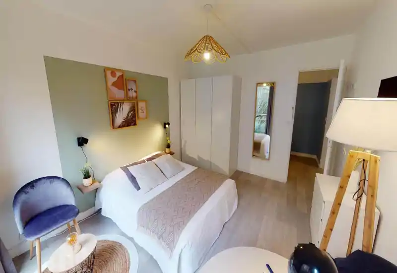 Bright, styled bedroom with a double bed, wardrobe and cozy seating area; neutral tones and soft textiles create a calm atmosphere ideal for restful stays.