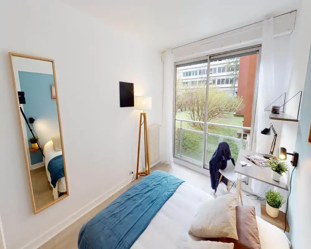Camera da letto luminosa e curata con letto matrimoniale, tessili accoglienti e scrivania vicino alla finestra con vista sul verde. Ampie porte scorrevoli assicurano luce naturale e un arredo moderno e tranquillo.
