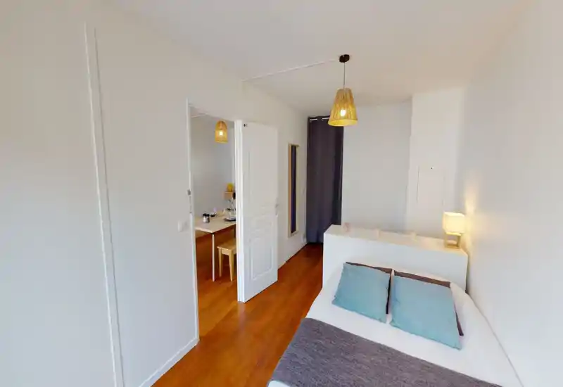 Chambre lumineuse et bien rangée avec lit double, oreillers confortables et éclairage chaleureux de chevet — parfaite pour une annonce mettant en avant le confort et un design épuré.