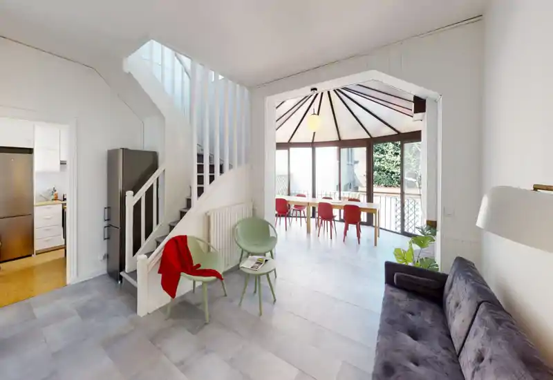Soggiorno luminoso e arioso con divano confortevole, sedute moderne e una grande alcova pranzo illuminata dalla luce naturale: ideale per convivialità e collegamento indoor–outdoor.
