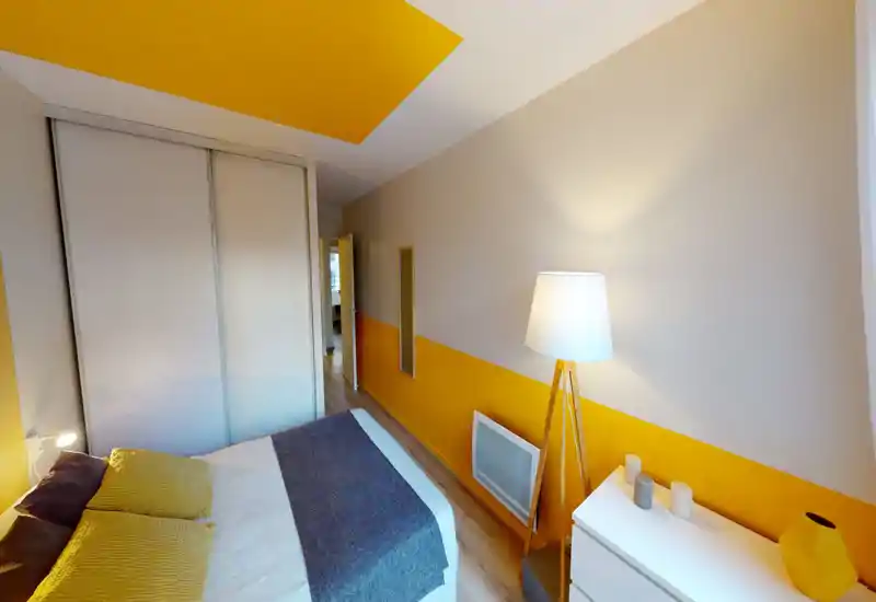 Camera da letto moderna e luminosa con letto ampio con biancheria bianca e grigia, parete e soffitto con accenti gialli, armadio scorrevole integrato e lampada da terra in legno. Stile pulito e tessili accoglienti la rendono invitante.