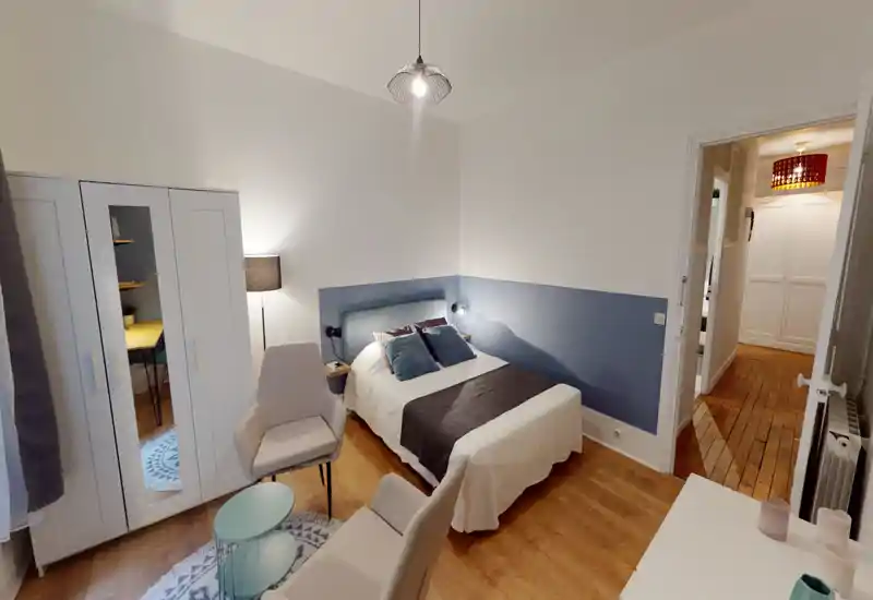 Bright, well-styled bedroom with a double bed, upholstered headboard and coordinated cushions; wardrobe and seating area create a comfortable, ready-to-rent space.