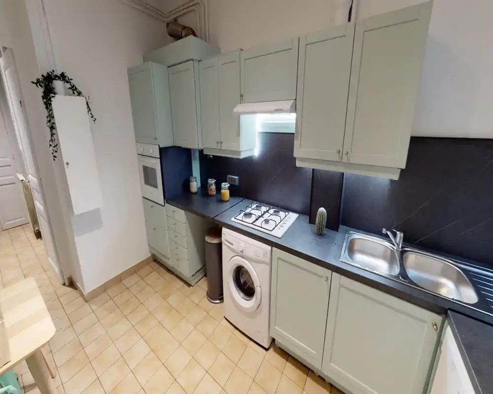 Bright, modern kitchen with pastel cabinetry, gas hob, built-in oven and a double sink; compact appliances including a washing machine under the counter and neat countertop storage.