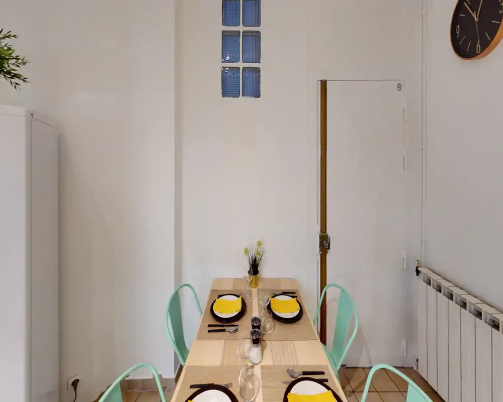 Bright, neatly set dining area with a wooden table for four, mint-colored chairs and simple decorative details — ideal for meal listings.