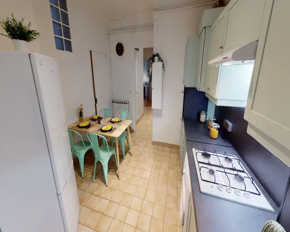 Bright, modern kitchen with mint-green cabinets, gas hob, and a small dining table set for four. Clean counters, glass storage jars and coordinated chairs make it feel homely and practical for short-term rentals.