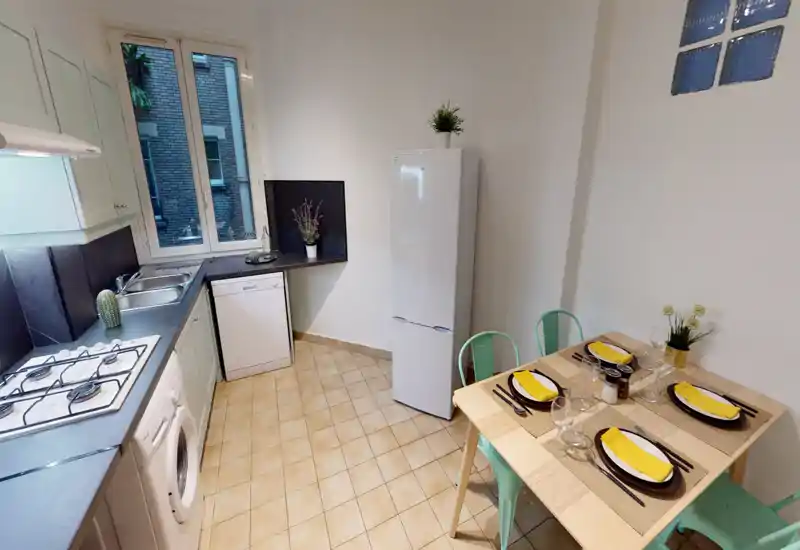 Bright, well-equipped kitchen with gas hob, sink, dishwasher and tall fridge; a small dining table set for four gives a cozy eating area.