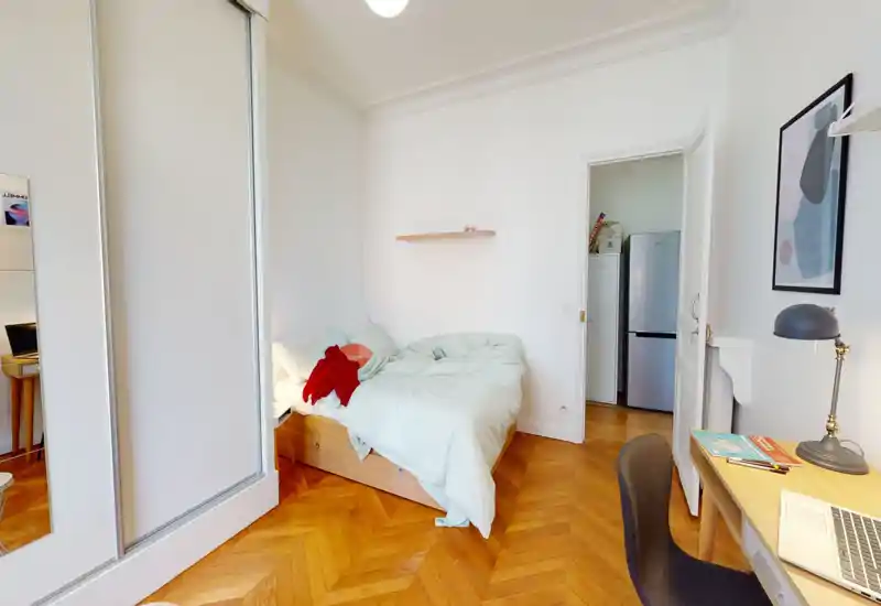 Chambre lumineuse et accueillante avec un lit double en linge clair, parquet en bois et un petit bureau — idéale pour les locations courte durée.