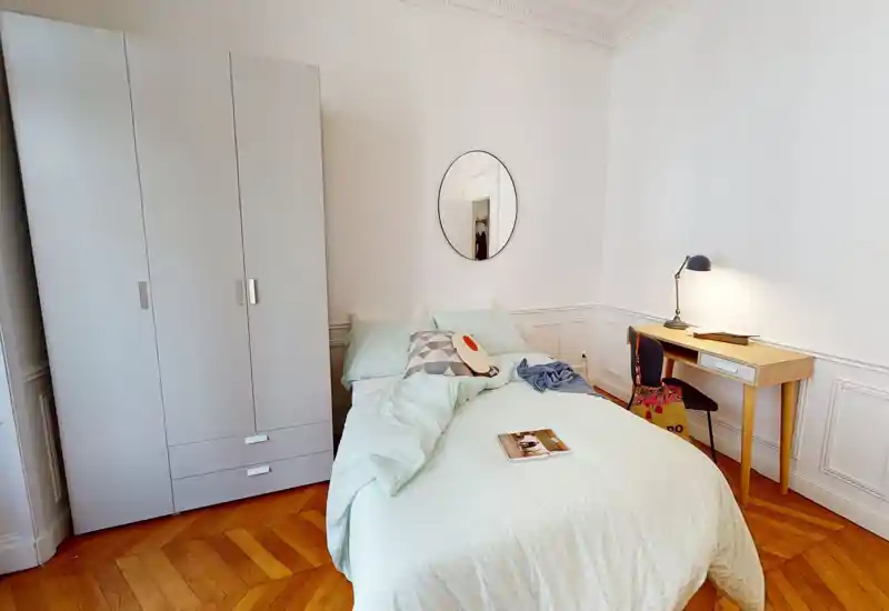 Camera da letto luminosa e curata con letto matrimoniale, biancheria color menta, armadio e una piccola scrivania con lampada—ideale per una o due persone.