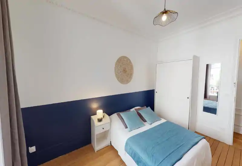 Chambre double lumineuse et bien décorée avec touches bleu-vert, table de chevet et armoire — idéale pour une location courte durée.