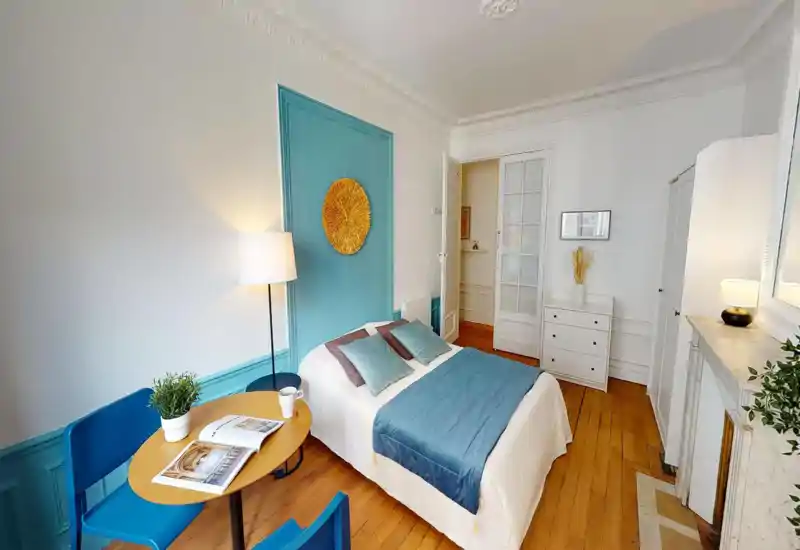 Bright, well-styled bedroom with a double bed, teal accent wall and coordinated textiles. Wooden floors and tasteful furnishings create a warm, inviting atmosphere ideal for short-term stays.