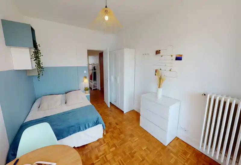 Dormitorio luminoso y bien presentado con cama doble, pared en azul y textiles coordinados. La habitación dispone de armario, cómoda y una pequeña zona de escritorio — ideal para una persona o pareja.