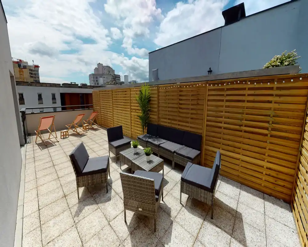 Terrasse privée ensoleillée avec salon de jardin, chiliennes et claustra en bois pour l'intimité — idéale pour se détendre ou recevoir en plein air.