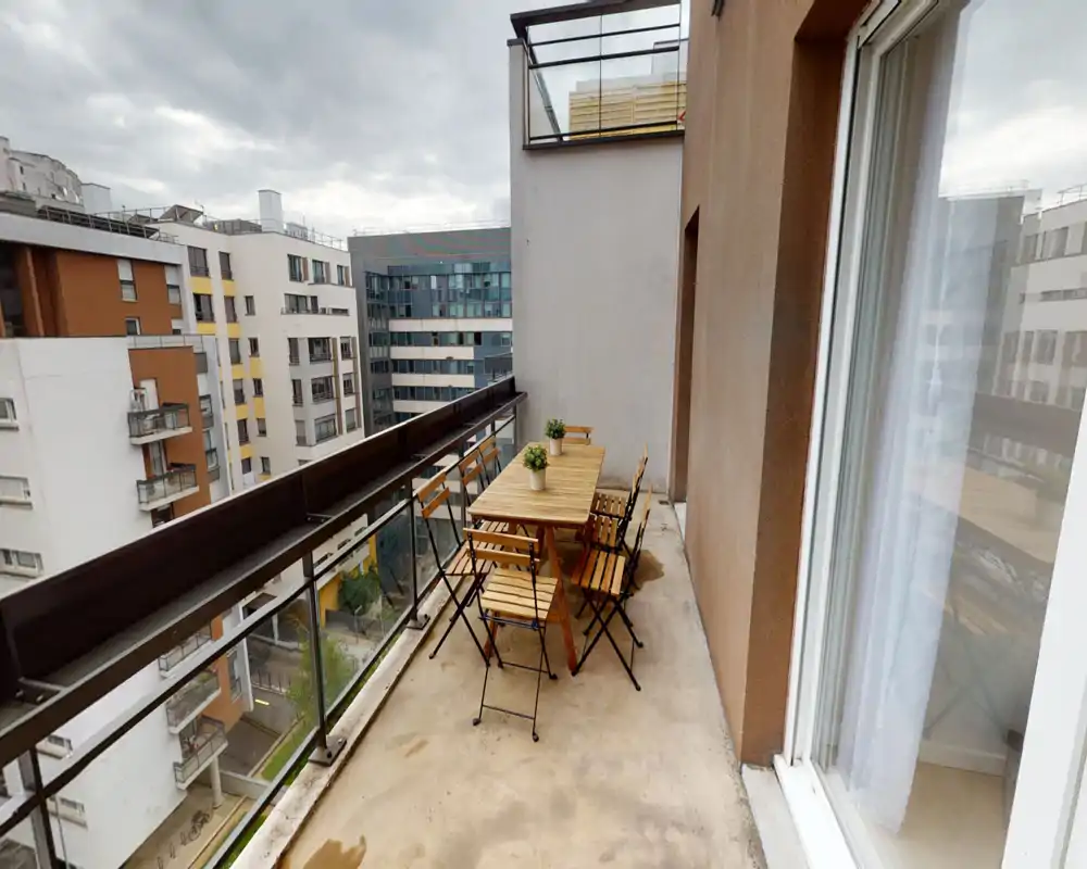 Balcon en ville avec salon de jardin en bois pour six et garde-corps en verre — parfait pour repas en plein air et détente avec vue urbaine.
