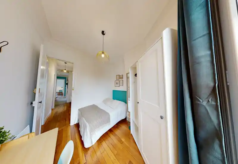 Camera compatta e luminosa con letto singolo, pavimento in legno e armadio a incasso. La luce naturale mette in risalto la biancheria pulita e la decorazione delle pareti, perfetta per un soggiorno accogliente.