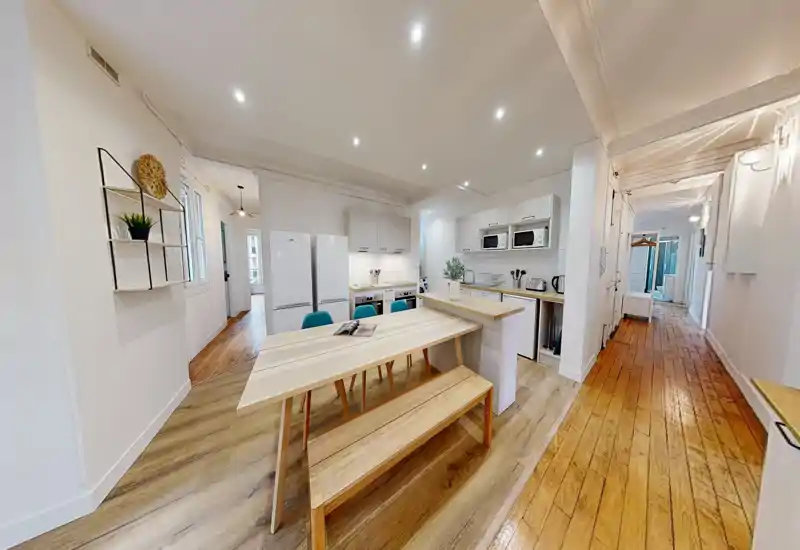Cucina moderna a vista con tavolo e panca in legno, mobili bianchi e elettrodomestici integrati; luminosa, ariosa e ben allestita per un annuncio.