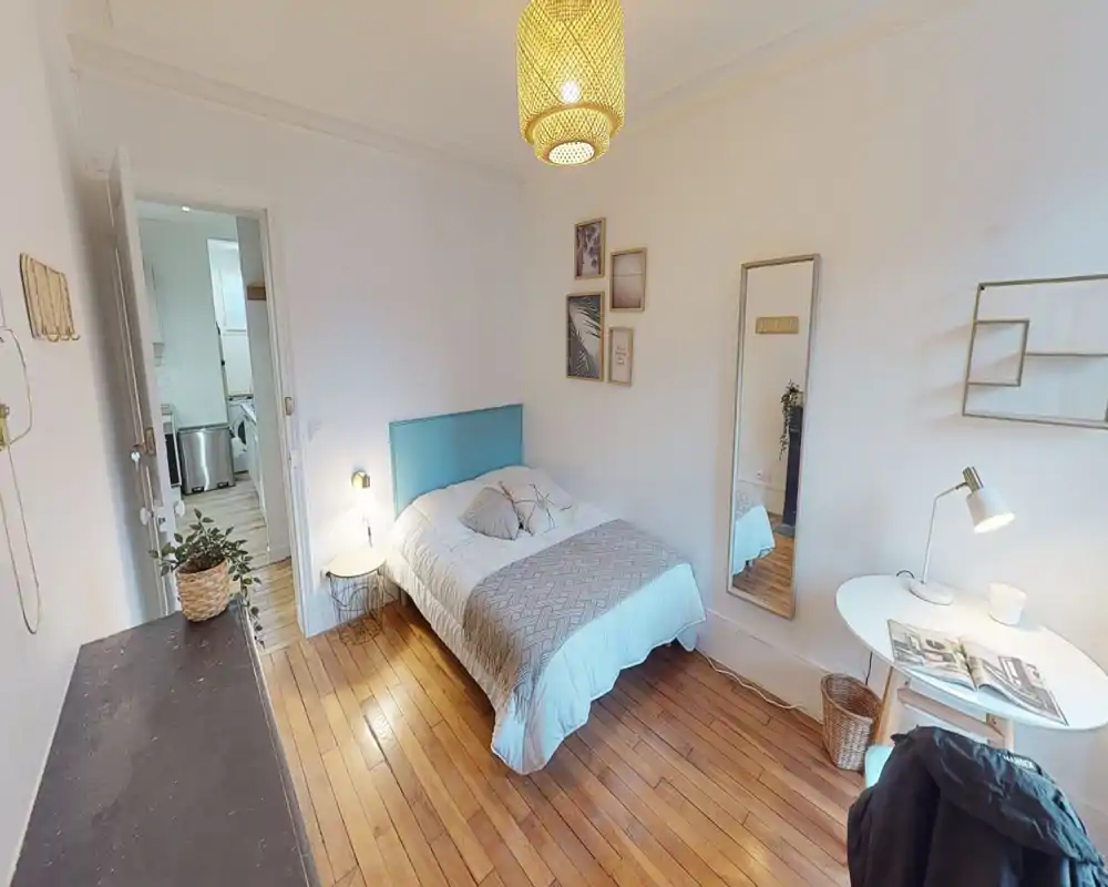 Camera da letto luminosa e accogliente con letto matrimoniale, testiera turchese e pavimento in legno; tessili morbidi, lampade da comodino e specchio intero creano un ambiente curato.