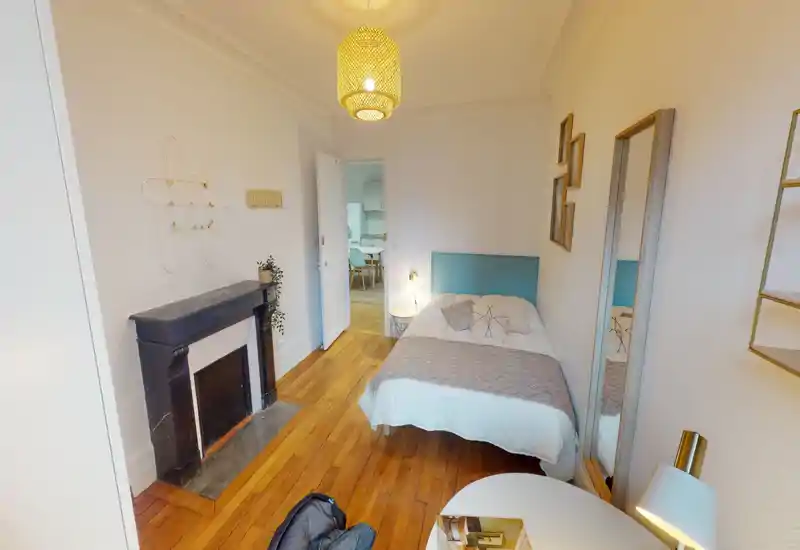 Camera da letto compatta e raffinata con letto matrimoniale, tessili morbidi e pavimenti in legno caldo; buona luce e dettagli decorativi per un ambiente accogliente.