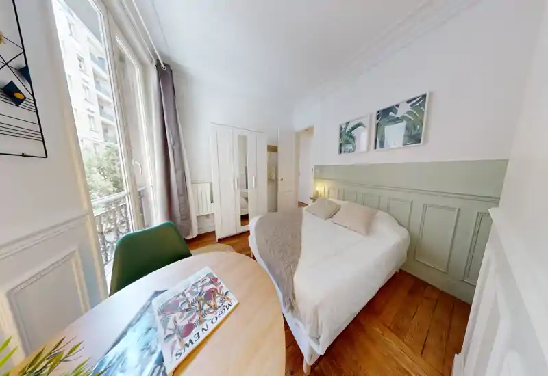 Camera da letto luminosa e accogliente con letto matrimoniale, biancheria morbida e cuscini decorativi, ampia finestra con luce naturale, armadio e piccolo tavolo — ideale per un soggiorno confortevole.