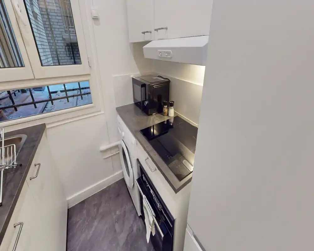 Compact modern kitchen with a built-in oven, induction hob, microwave and washing machine. Bright, efficiently organized space ideal for short-term stays.