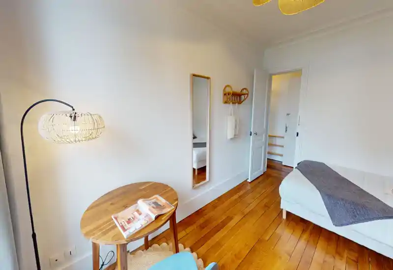 Camera da letto luminosa e accogliente con letto ben rifatto, pavimento in legno e tessili morbidi che creano un'atmosfera calda.
