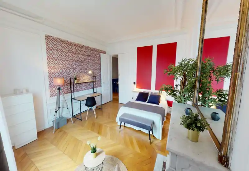 Camera da letto luminosa e di stile con letto matrimoniale, tessili accoglienti, scrivania e piante decorative. Stucchi classici e parquet aggiungono carattere e molta luce naturale.