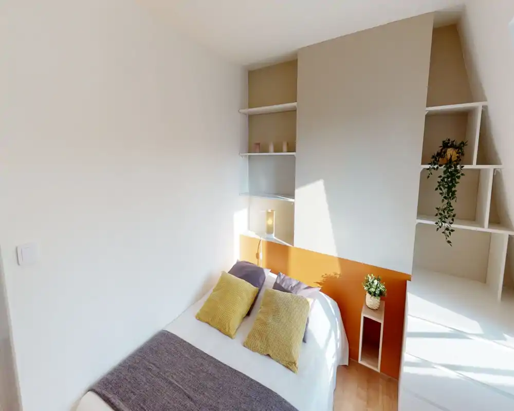 Dormitorio luminoso y bien decorado con cama doble, cojines con textura y estanterías empotradas. La luz natural y los tonos cálidos crean un ambiente acogedor, perfecto para anuncios.