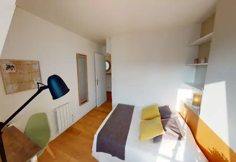 Bright, cozy bedroom with a double bed dressed in neutral linens and yellow accent cushions, wooden floors and built-in shelving beside the headboard.